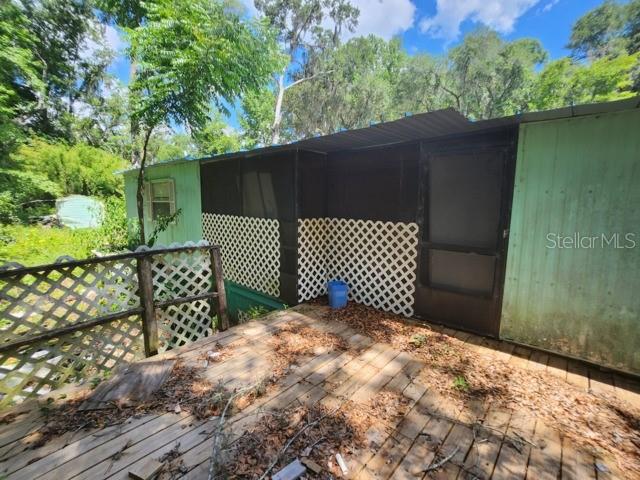 A wooden deck leads to a screened-in porch with lattice skirting on a mobile home — 3140 NE 162ND PLACE, CITRA, FL