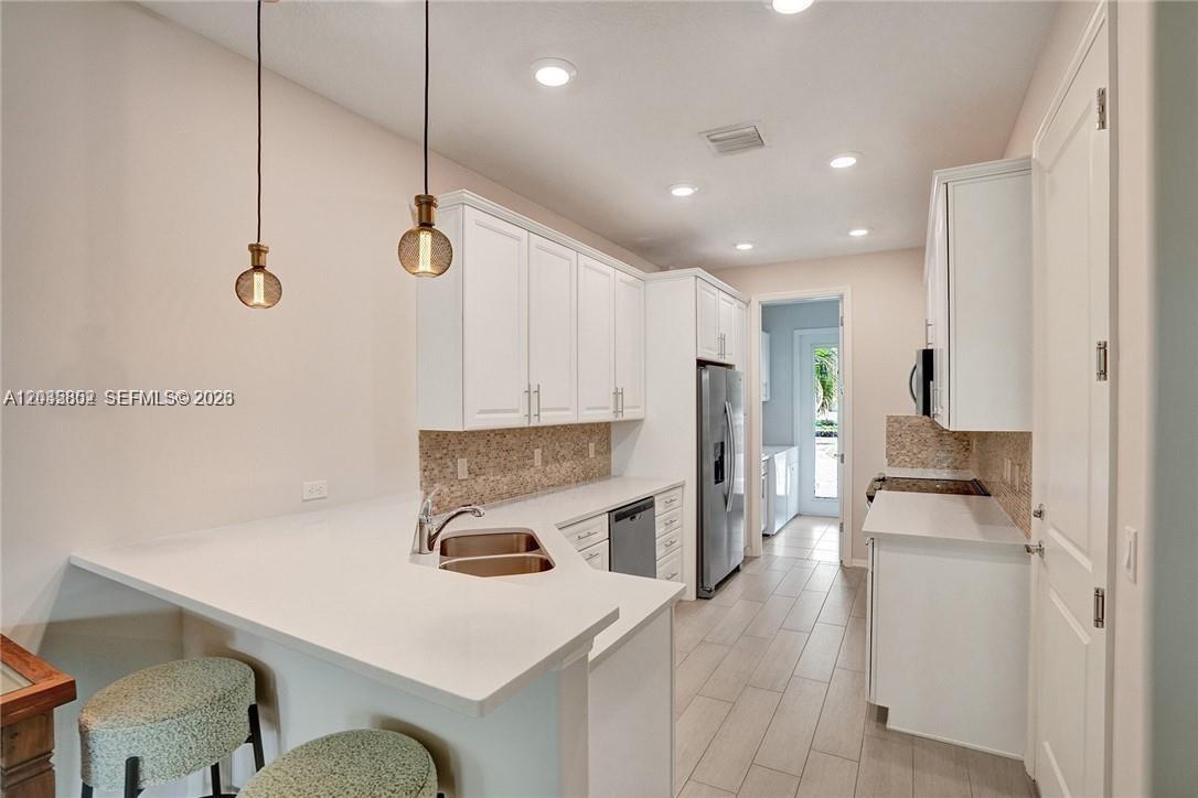 A modern kitchen features white cabinets, quartz countertops, stainless steel appliances, and two pendant lights — 5140 Eucalyptus Dr # 5, Hollywood FL 33021, HOLLYWOOD, FL