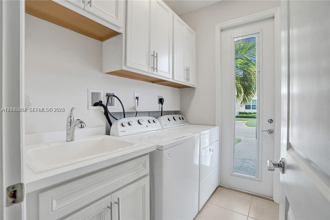 A laundry room features white cabinets, a utility sink, and a door leading outside — 5140 Eucalyptus Dr # 5, Hollywood FL 33021, HOLLYWOOD, FL