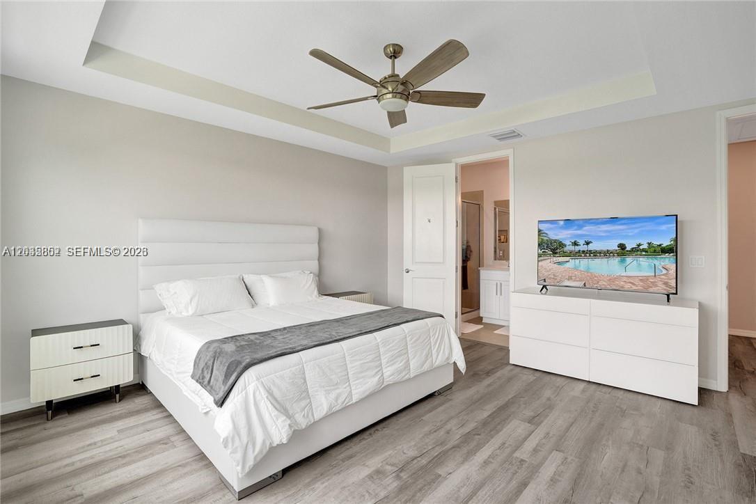 A bedroom features a white bed, a white dresser with a television, and wood flooring — 5140 Eucalyptus Dr # 5, Hollywood FL 33021, HOLLYWOOD, FL