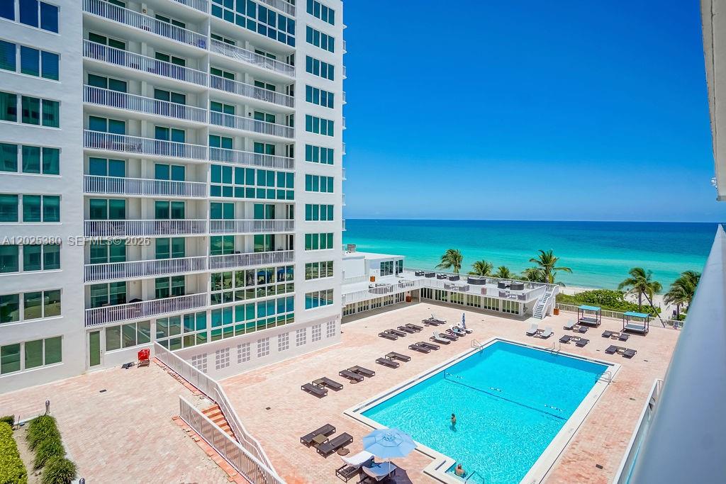 An elevated view of a swimming pool deck next to a multi-story white apartment building — 5401 Collins Ave # 920, Miami Beach FL 33140, MIAMI BEACH, FL