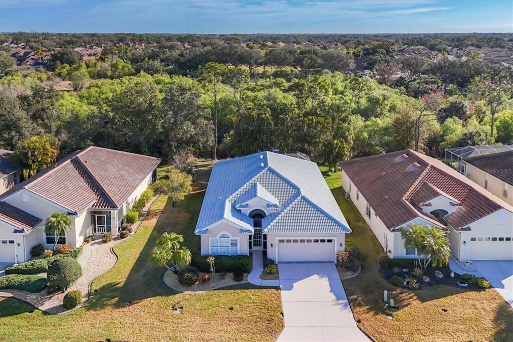 An aerial view shows a suburban house with a light-colored roof and a concrete driveway — 711 BACK NINE DRIVE, VENICE, FL