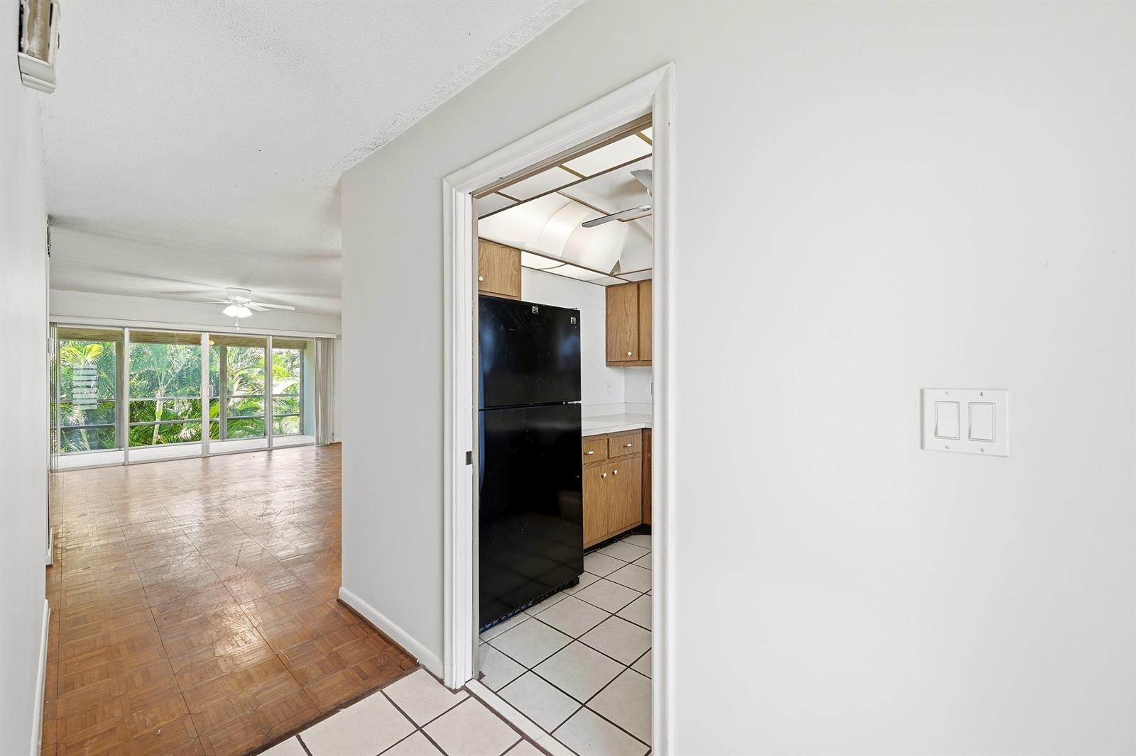 A view from a tiled entryway into a kitchen with wood cabinets and a living area — 2160 NE 36th Street # 37, Lighthouse Point FL 33064, LIGHTHOUSE POINT, FL