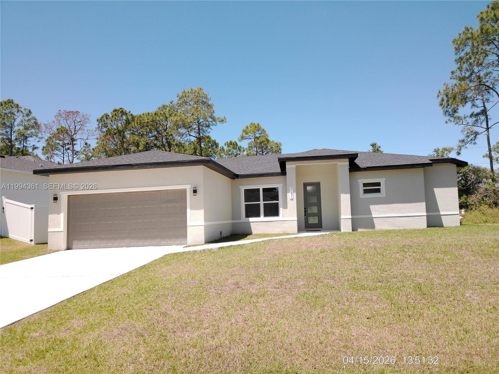 A single-story house with a beige stucco exterior, a two-car garage, and a grass lawn — 791 Reading ST SW, Palm Bay FL 32909, PALM BAY, FL