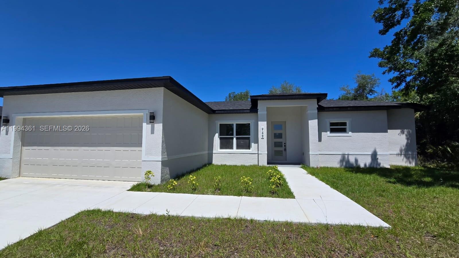 A single-story house with a beige stucco exterior, a two-car garage, and a dark roof — 791 Reading ST SW, Palm Bay FL 32909, PALM BAY, FL