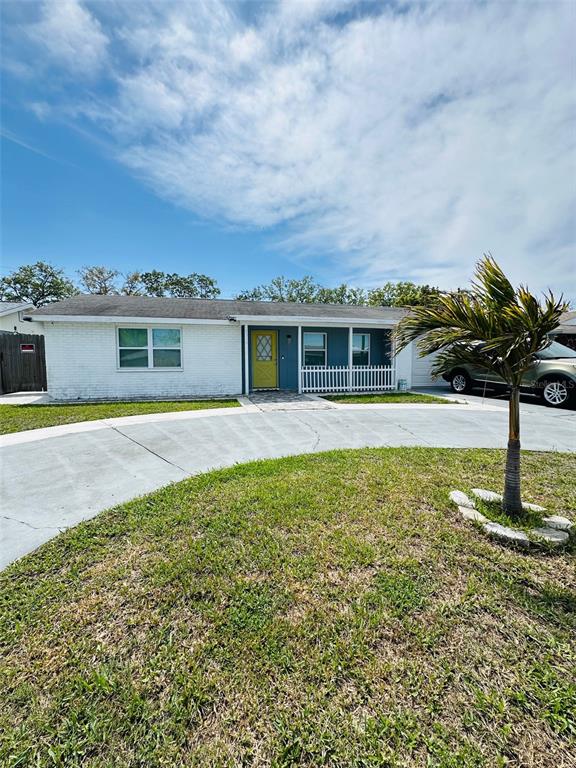 A single-story white brick house features a bright yellow front door and a curved driveway — 6310 WESTPORT DRIVE, PORT RICHEY, FL
