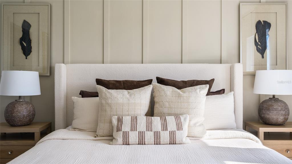 A bedroom features a white upholstered headboard, two bedside lamps, and framed wall art — 3907 ALTITUDE RUN, DAVENPORT, FL