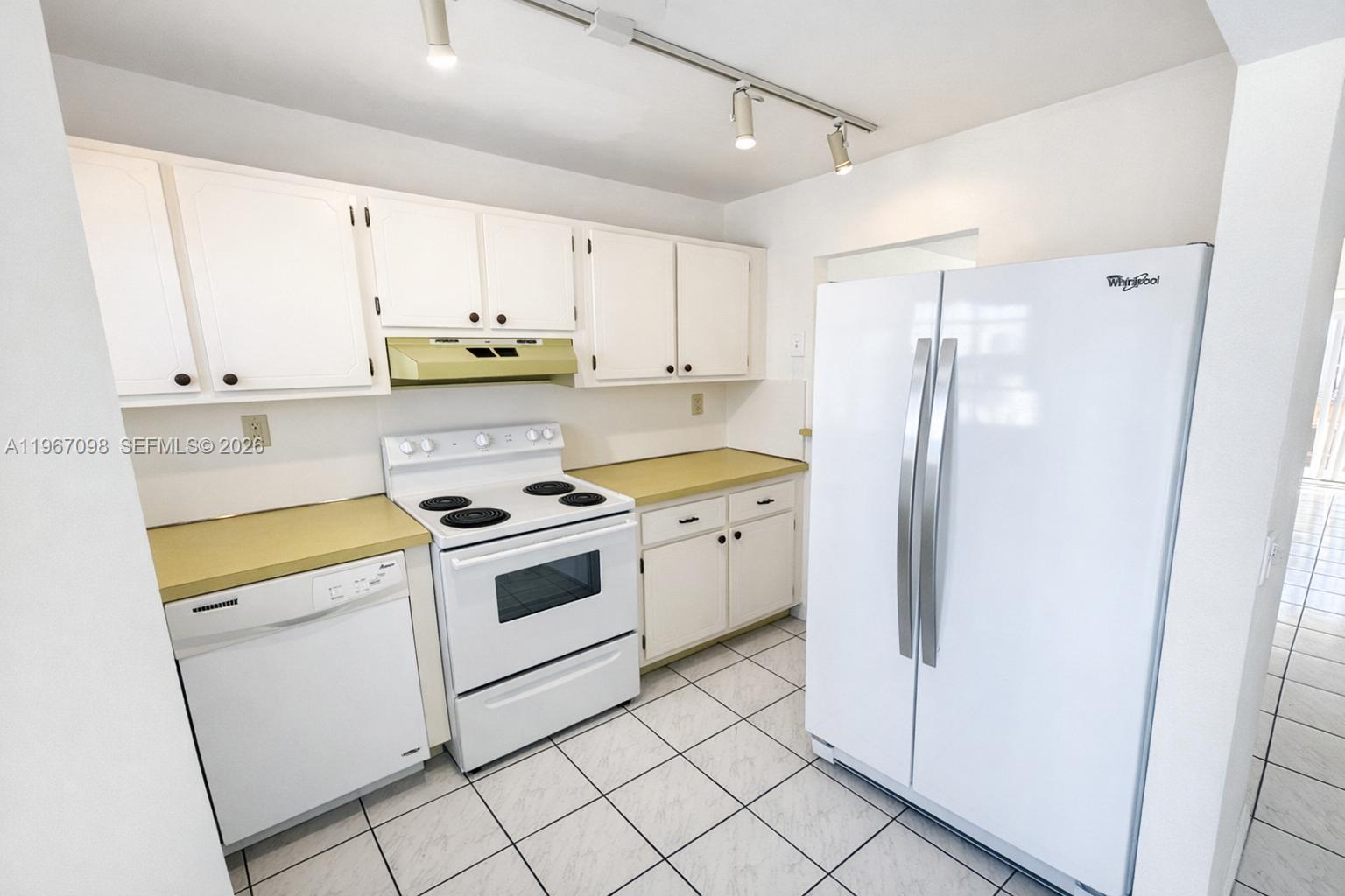 A kitchen features white cabinets, white appliances, yellow countertops, and white tile flooring — 1630 W 46th St # 514B, Hialeah FL 33012, HIALEAH, FL