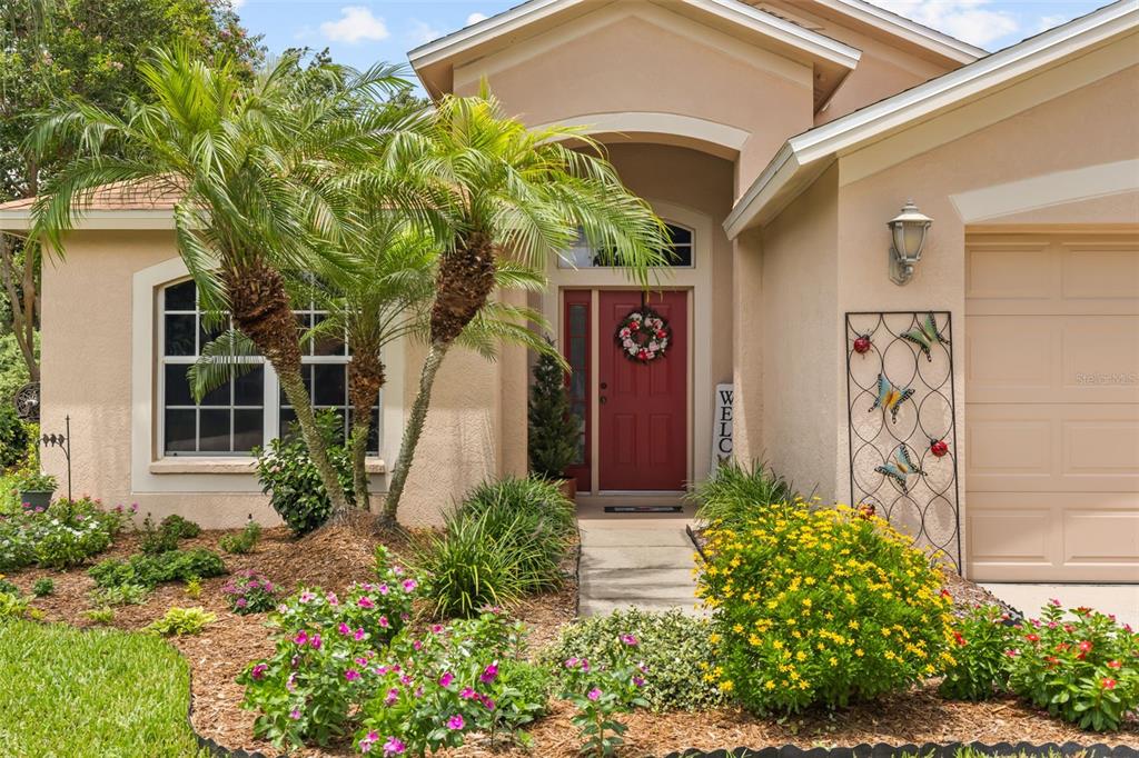 The exterior of a single-story house features a red front door and a palm tree — 13813 SIGLER STREET, RIVERVIEW, FL