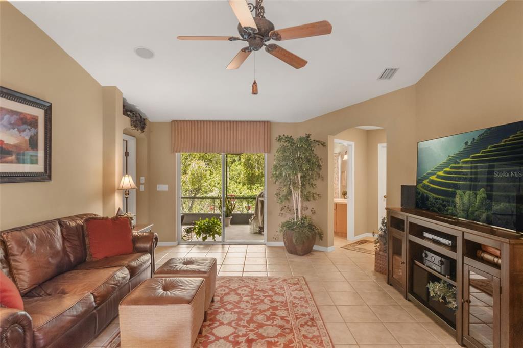 A living room with tile flooring, a leather sofa, a television, and a sliding glass door — 13813 SIGLER STREET, RIVERVIEW, FL