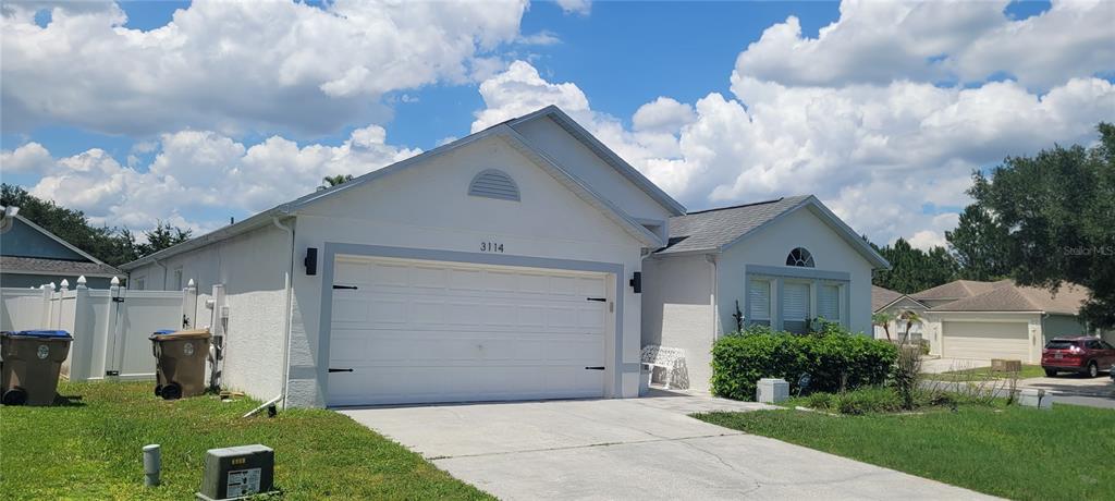 A single-story house with a white stucco exterior, a two-car garage, and a concrete driveway — 3114 STERN COURT, KISSIMMEE, FL