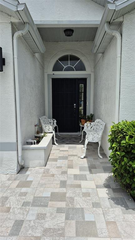 A covered entryway features a tiled floor, two white metal benches, and a dark door — 3114 STERN COURT, KISSIMMEE, FL