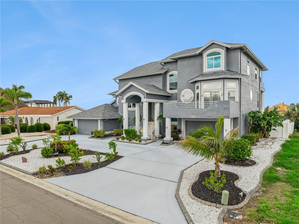 A multi-story gray house with a concrete driveway, a front porch, and landscaped rock beds — 807 CHIPAWAY DRIVE, APOLLO BEACH, FL