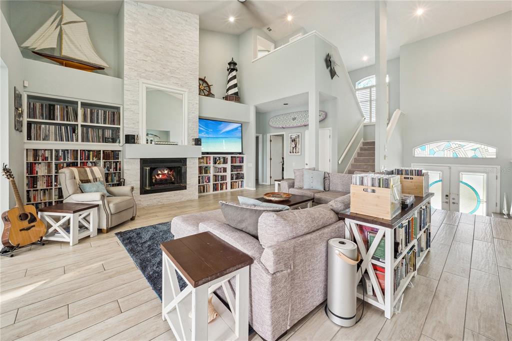A spacious living room features a stone fireplace, built-in bookshelves, and a large sectional sofa — 807 CHIPAWAY DRIVE, APOLLO BEACH, FL