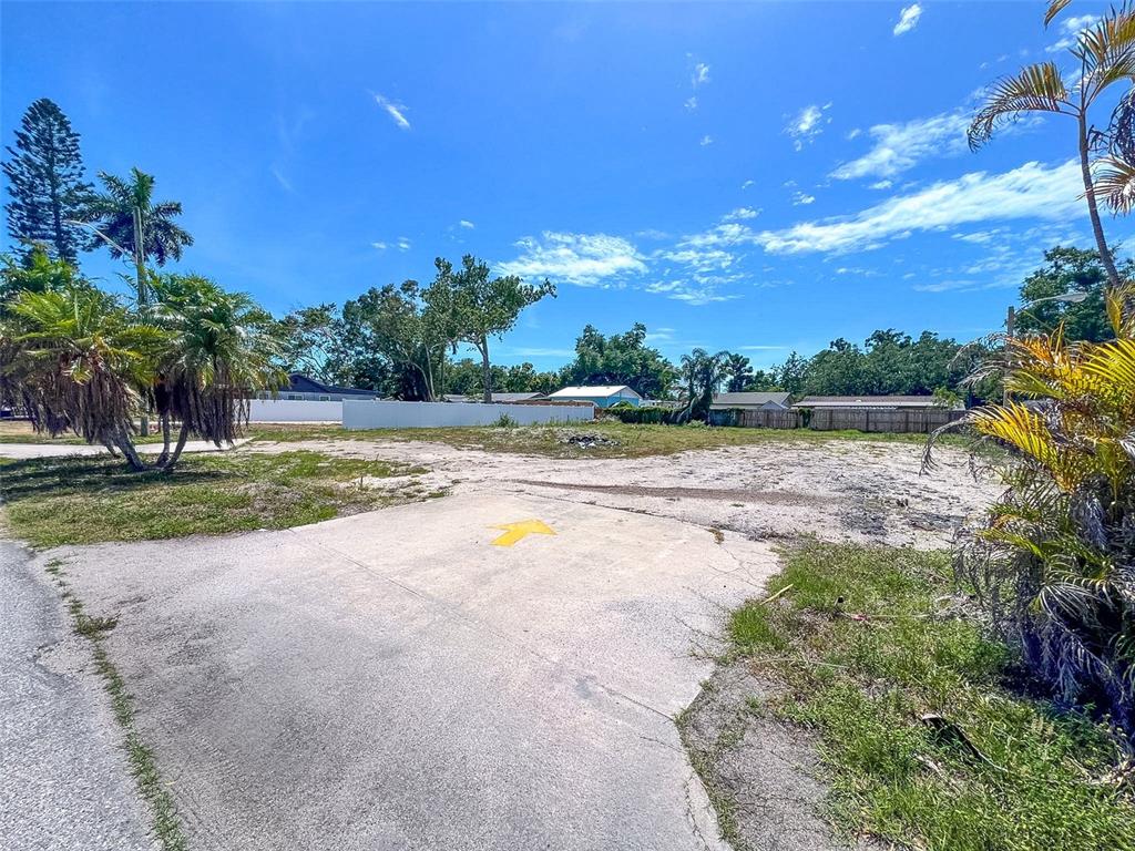 A vacant, sandy lot features a concrete driveway entrance with a yellow arrow marking — 35TH STREET W, BRADENTON, FL