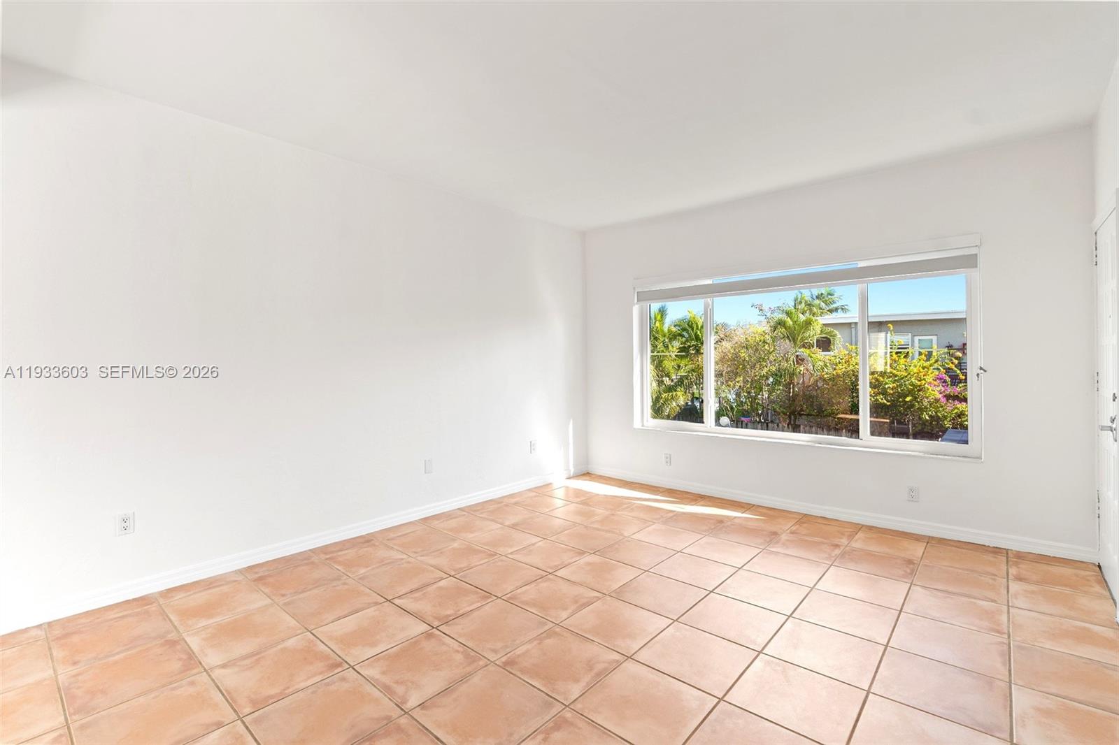 An empty room with white walls, tan tile flooring, and a large window — 1925 Calais Drive # 6, Miami Beach FL 33141, MIAMI BEACH, FL