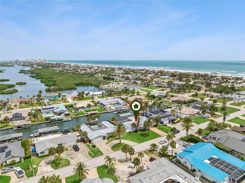 An aerial view shows a waterfront house with a pool and dock in a coastal neighborhood — 106 ANCHOR DRIVE, PONCE INLET, FL
