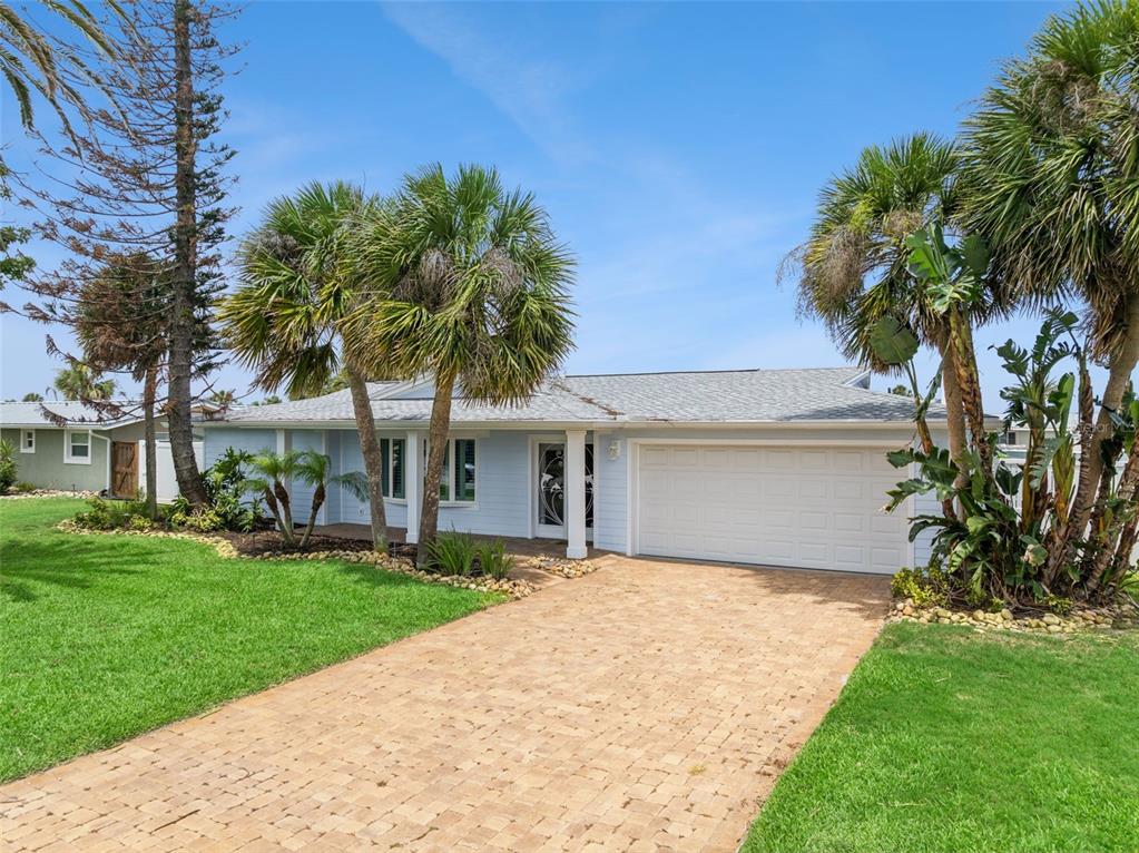 A light blue single-story house features a paved driveway, a white garage door, and palm trees — 106 ANCHOR DRIVE, PONCE INLET, FL