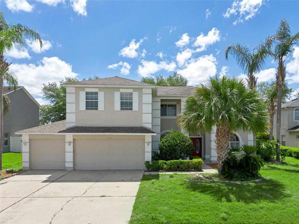 A two-story house with a beige stucco exterior, a three-car garage, and a palm tree — 2205 WINTERMERE POINTE DRIVE, WINTER GARDEN, FL