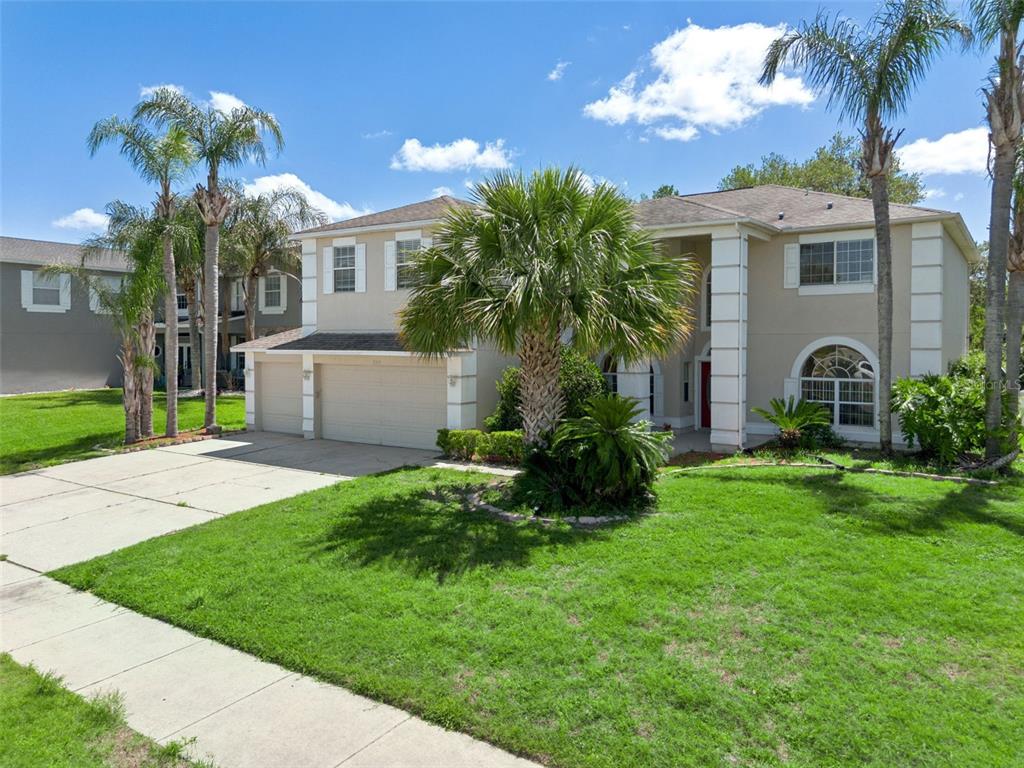A two-story suburban house with a three-car garage, palm trees, and a grassy front lawn — 2205 WINTERMERE POINTE DRIVE, WINTER GARDEN, FL
