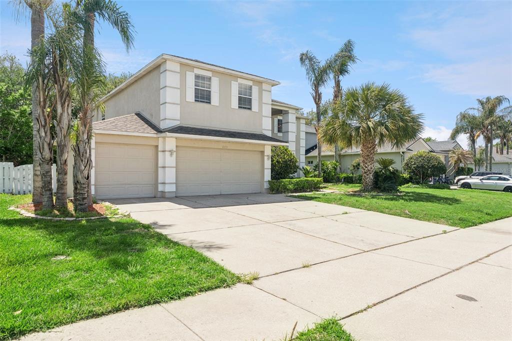 A two-story house with a beige stucco exterior, a three-car garage, and palm trees — 2205 WINTERMERE POINTE DRIVE, WINTER GARDEN, FL