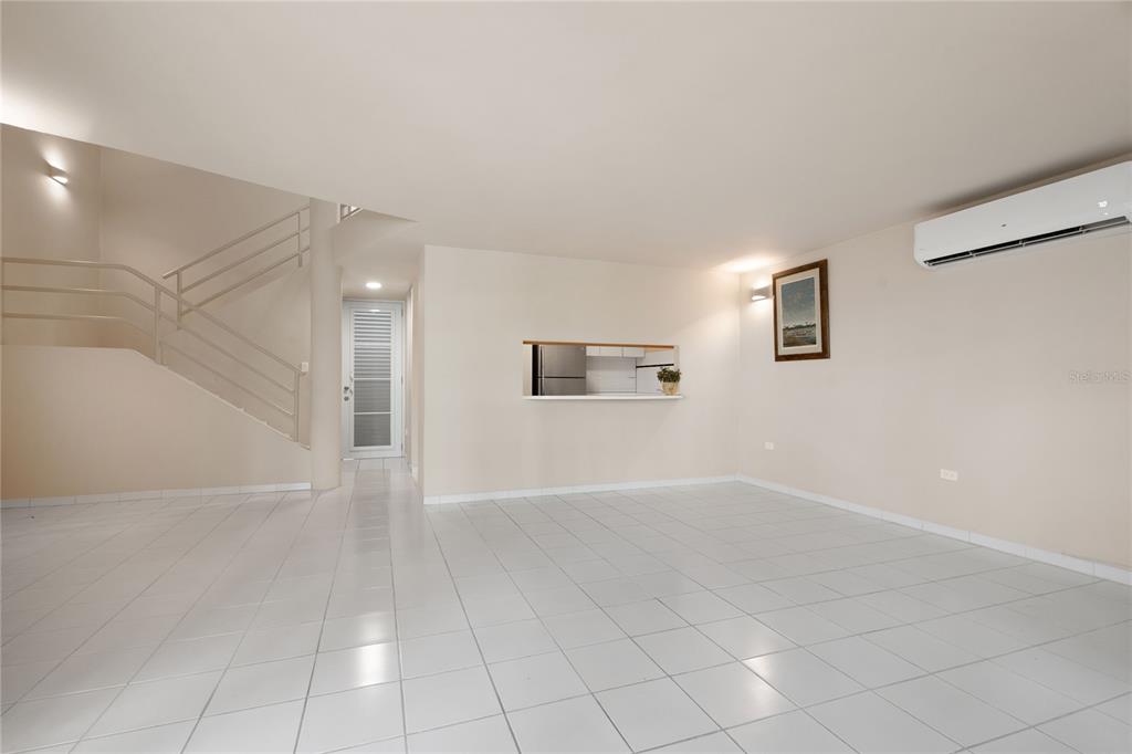 A bright living area features white tile flooring, a staircase, and a kitchen pass-through window — 125 PALMARINA CLUB UNIT 12, HUMACAO, PR