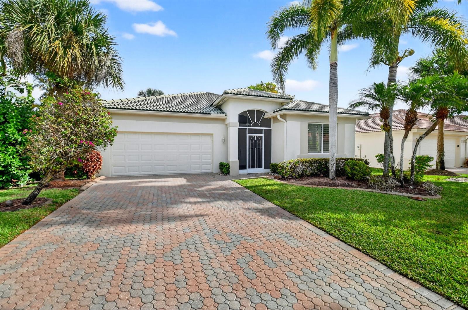 A single-story house with a paved driveway, white garage door, and palm trees in front — 8706 Bellido Circle, Boynton Beach FL 33472, BOYNTON BEACH, FL