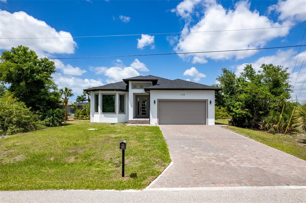 A single-story house with a white exterior, gray garage door, and a paved driveway — 178 LIME TREE PARK, ROTONDA WEST, FL
