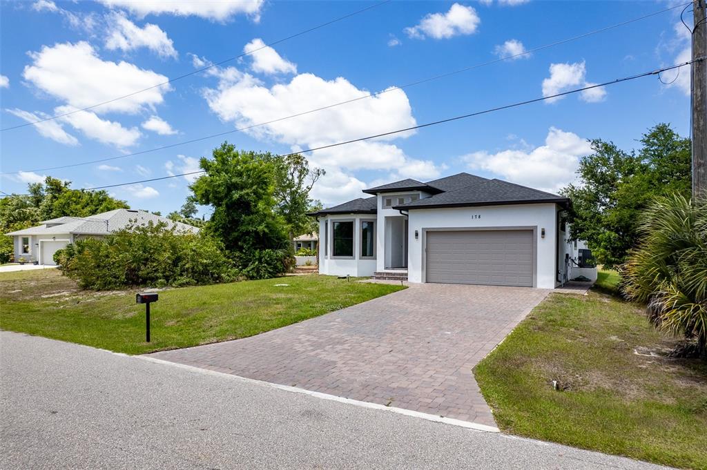 A single-story house with a white exterior, a gray garage door, and a paved driveway — 178 LIME TREE PARK, ROTONDA WEST, FL