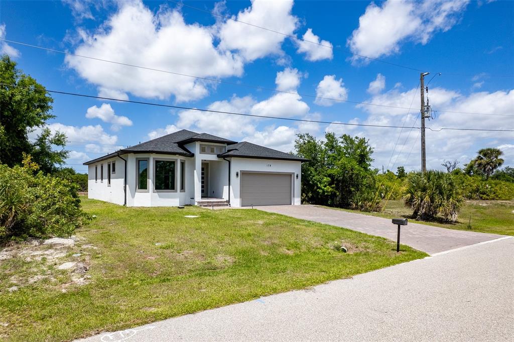 A single-story white house with a dark roof and a paved driveway under a sky — 178 LIME TREE PARK, ROTONDA WEST, FL