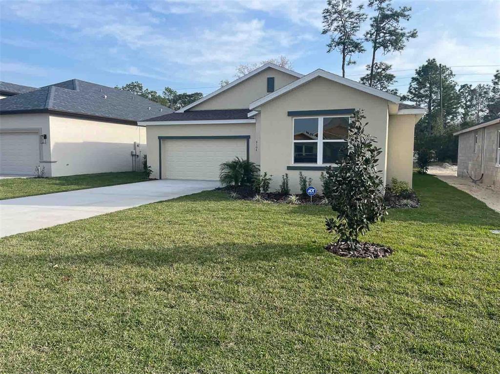 A single-story suburban house with a beige stucco exterior, a two-car garage, and a lawn — 8983 WADE STREET UNIT Plan 1, WEEKI WACHEE, FL