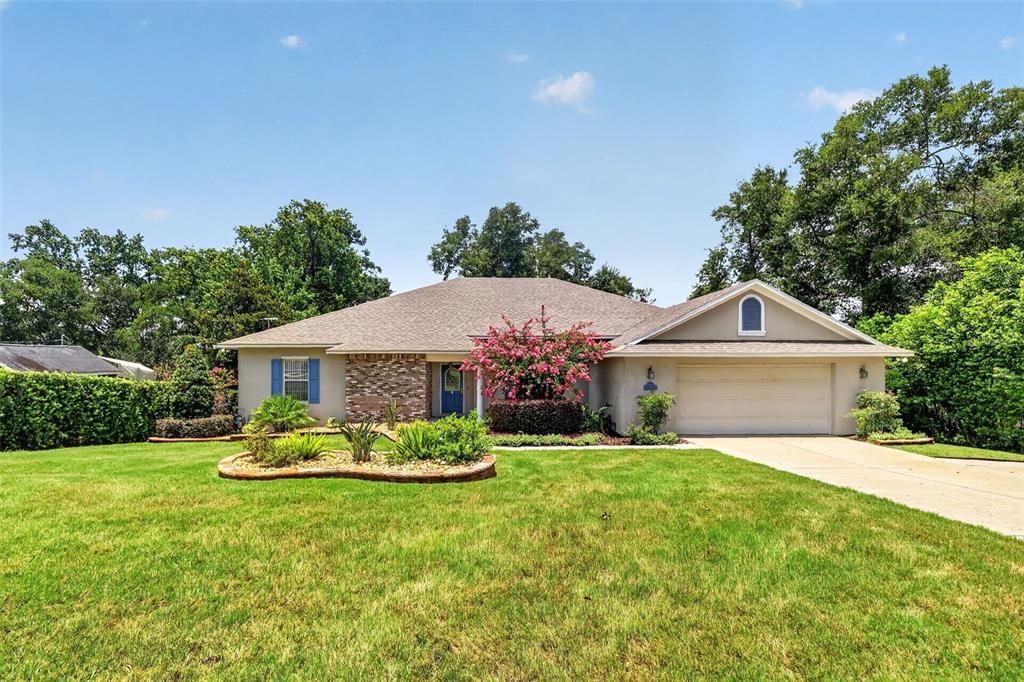A single-story house with a brick facade, a two-car garage, and a landscaped front yard — 705 HILLTOP COURT, MOUNT DORA, FL