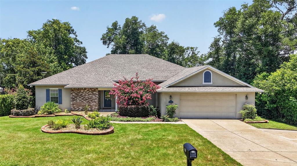 A single-story house with a brick facade, a two-car garage, and a landscaped front yard — 705 HILLTOP COURT, MOUNT DORA, FL