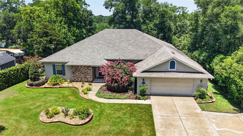 An aerial view of a single-story house with a hip roof, brick accents, and landscaping — 705 HILLTOP COURT, MOUNT DORA, FL
