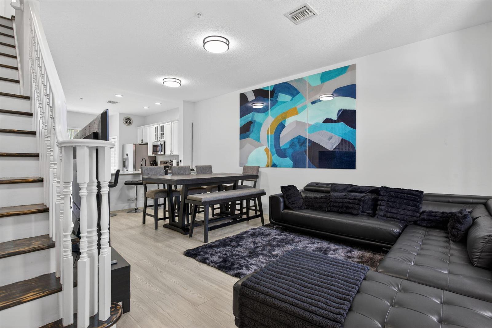 A living and dining area features a black sectional sofa, wooden table, and abstract art — 2457 NE 14th Street # 2457, Pompano Beach FL 33062, POMPANO BEACH, FL