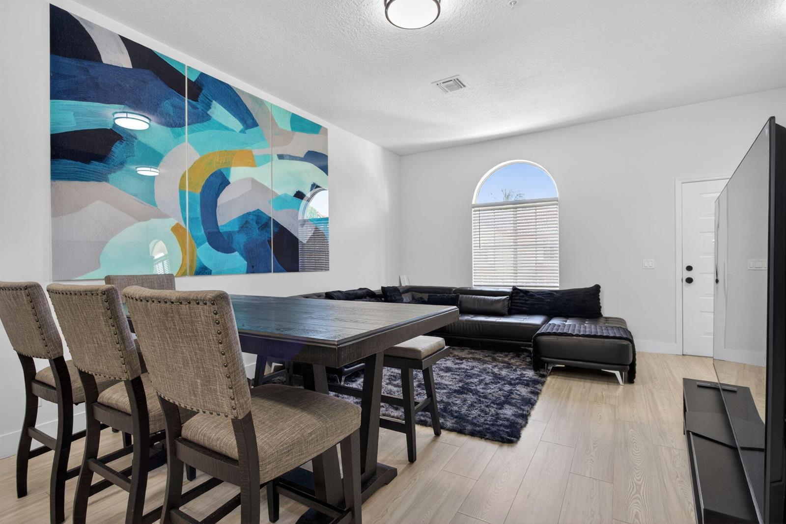 A dining area and living room feature a large abstract wall mural and wood flooring — 2457 NE 14th Street # 2457, Pompano Beach FL 33062, POMPANO BEACH, FL
