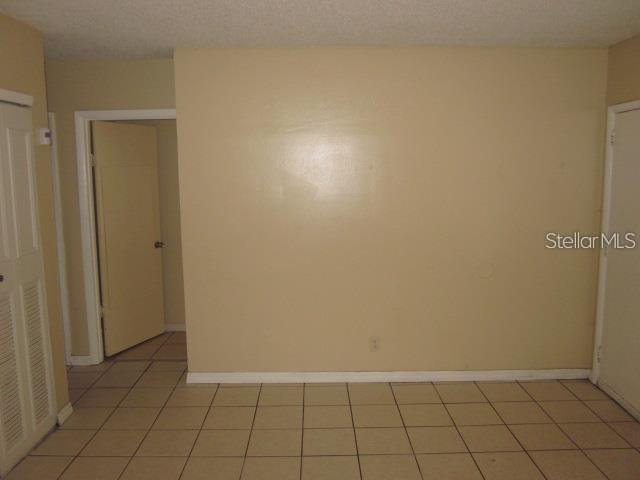 An interior view shows a room with beige walls, light-colored floor tiles, and two doors — 8619 N MULBERRY STREET UNIT A, TAMPA, FL