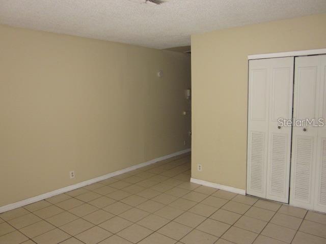A room with beige walls, tiled flooring, and white louvered closet doors — 8619 N MULBERRY STREET UNIT A, TAMPA, FL