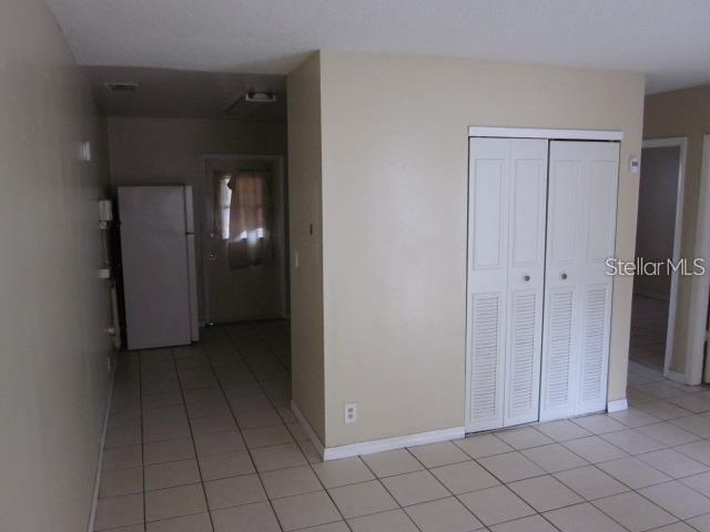 A room with light-colored tile flooring, a white refrigerator, and a white bi-fold closet door — 8619 N MULBERRY STREET UNIT A, TAMPA, FL