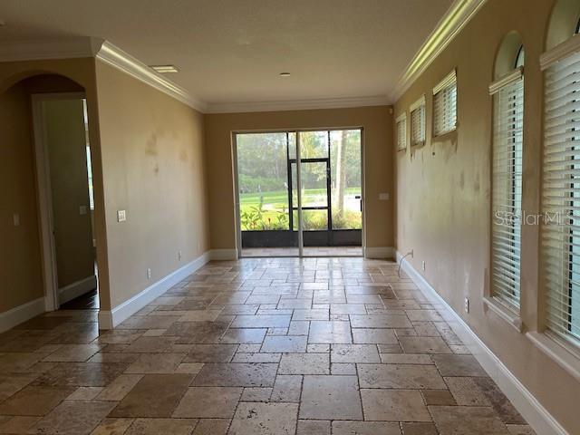 A room with tan walls, tile flooring, and large windows looking out to a screened patio — 10139 WILLOW GROVE COURT, ORLANDO, FL