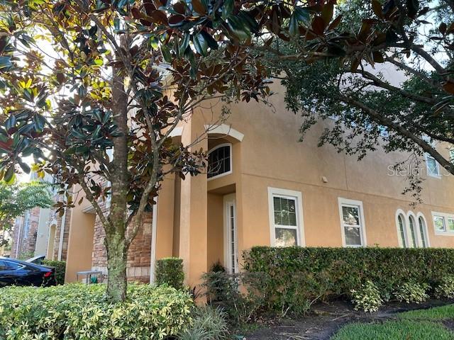 A two-story tan stucco building with stone accents and a large tree in the foreground — 10139 WILLOW GROVE COURT, ORLANDO, FL