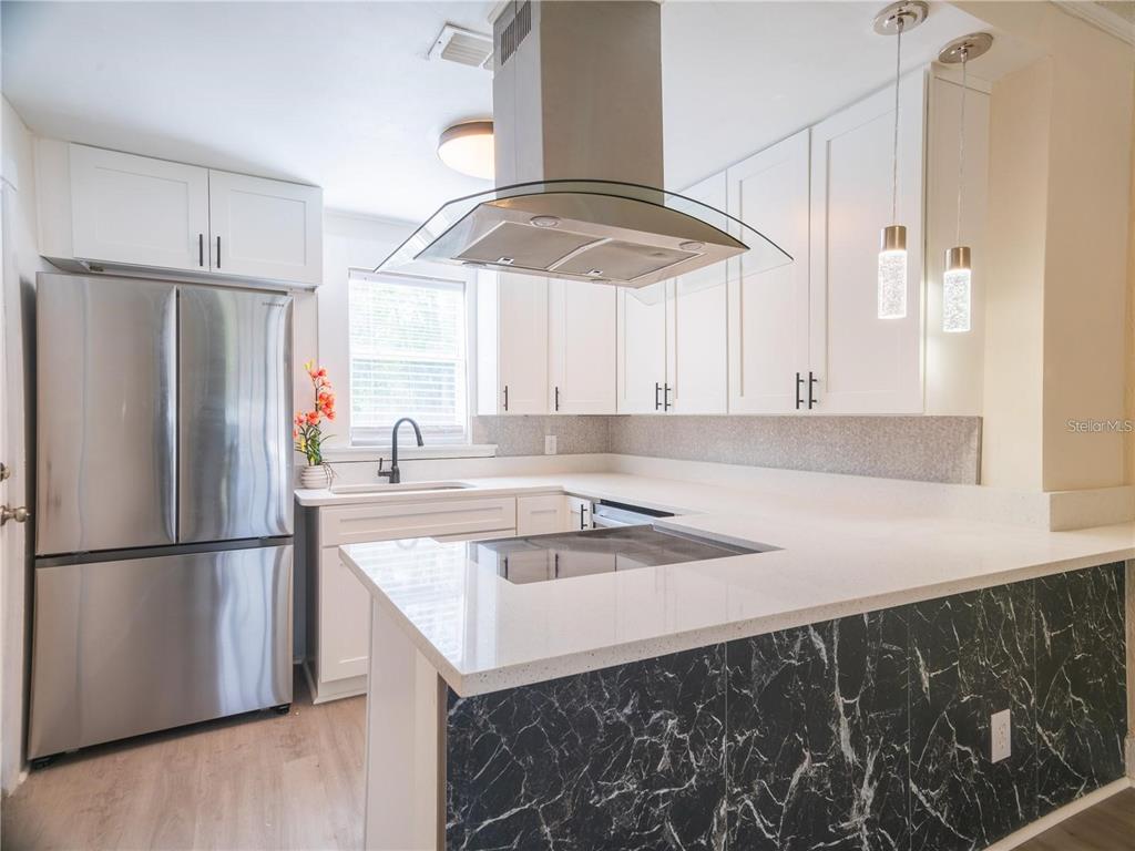 A modern kitchen features white cabinets, stainless steel appliances, and a black marble-patterned island base — 811 OVERSPIN DRIVE, WINTER PARK, FL