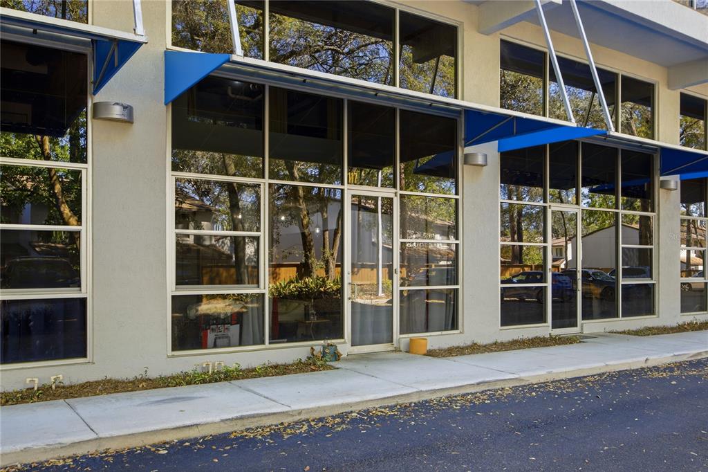 The exterior of a commercial building features large glass windows and blue metal awnings — 2515 SW 35TH PLACE UNIT 117, GAINESVILLE, FL