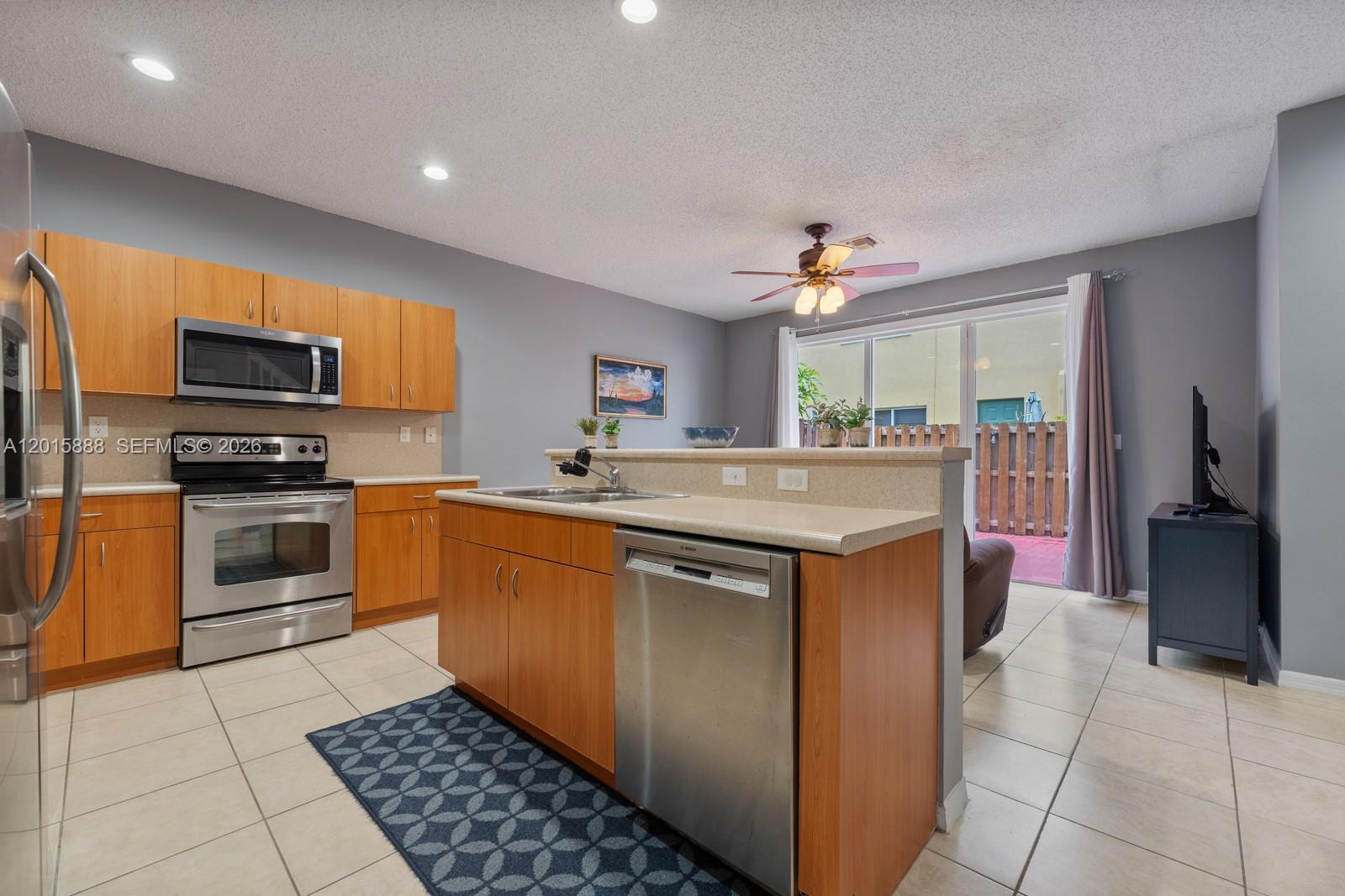 A kitchen with wood cabinets, stainless steel appliances, and a central island with a dishwasher — 934 NE 42nd Ter, Homestead FL 33033, HOMESTEAD, FL