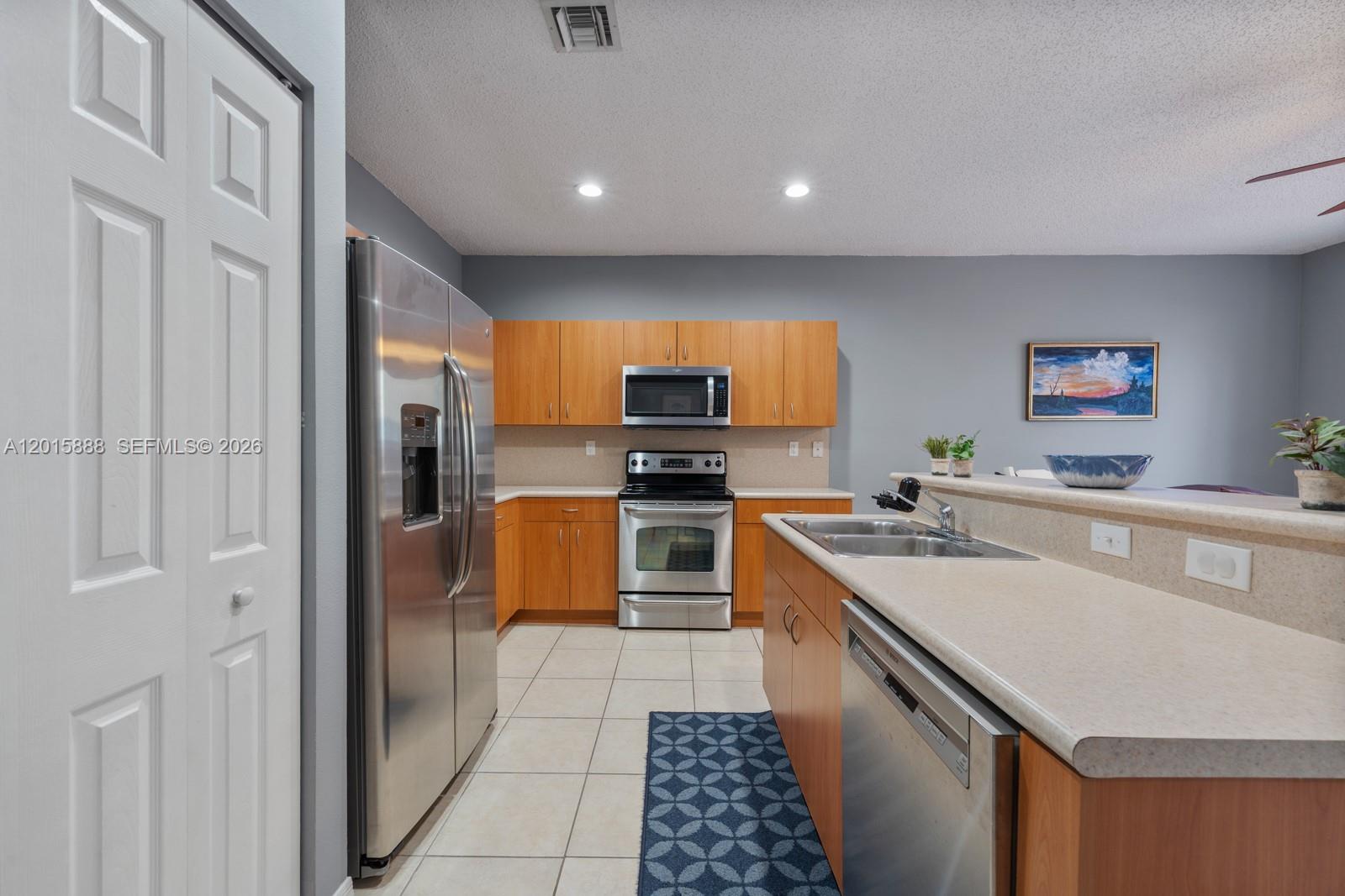 A kitchen features stainless steel appliances, wood cabinets, and a peninsula with a sink — 934 NE 42nd Ter, Homestead FL 33033, HOMESTEAD, FL