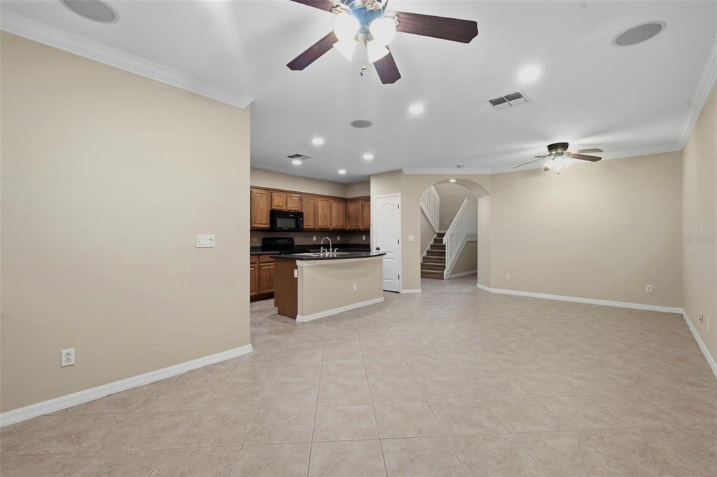 An open-concept kitchen with wood cabinets and a breakfast bar overlooks a large living area — 7212 STERLING POINT COURT, GIBSONTON, FL