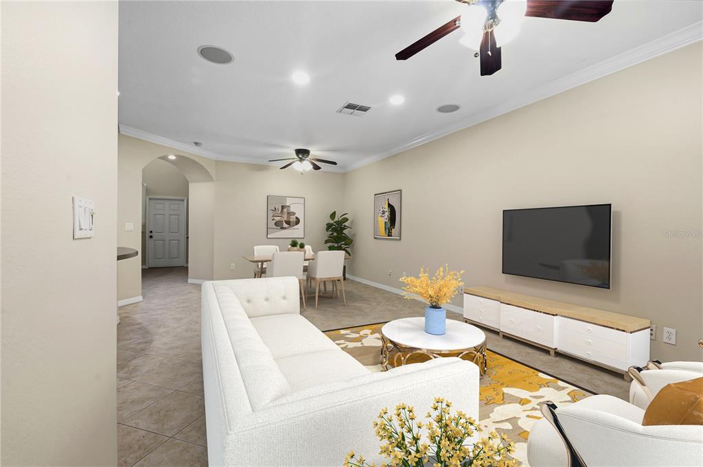 A living room with a white sofa, television, dining area, and tile flooring — 7212 STERLING POINT COURT, GIBSONTON, FL