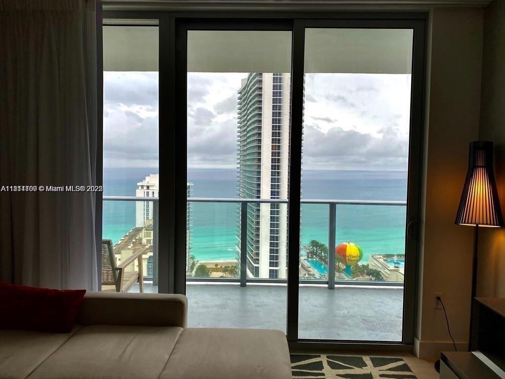 A view of the ocean and nearby high-rise buildings from a room with a sofa — 4010 S Ocean Dr # R1905, Hollywood FL 33019, HOLLYWOOD, FL