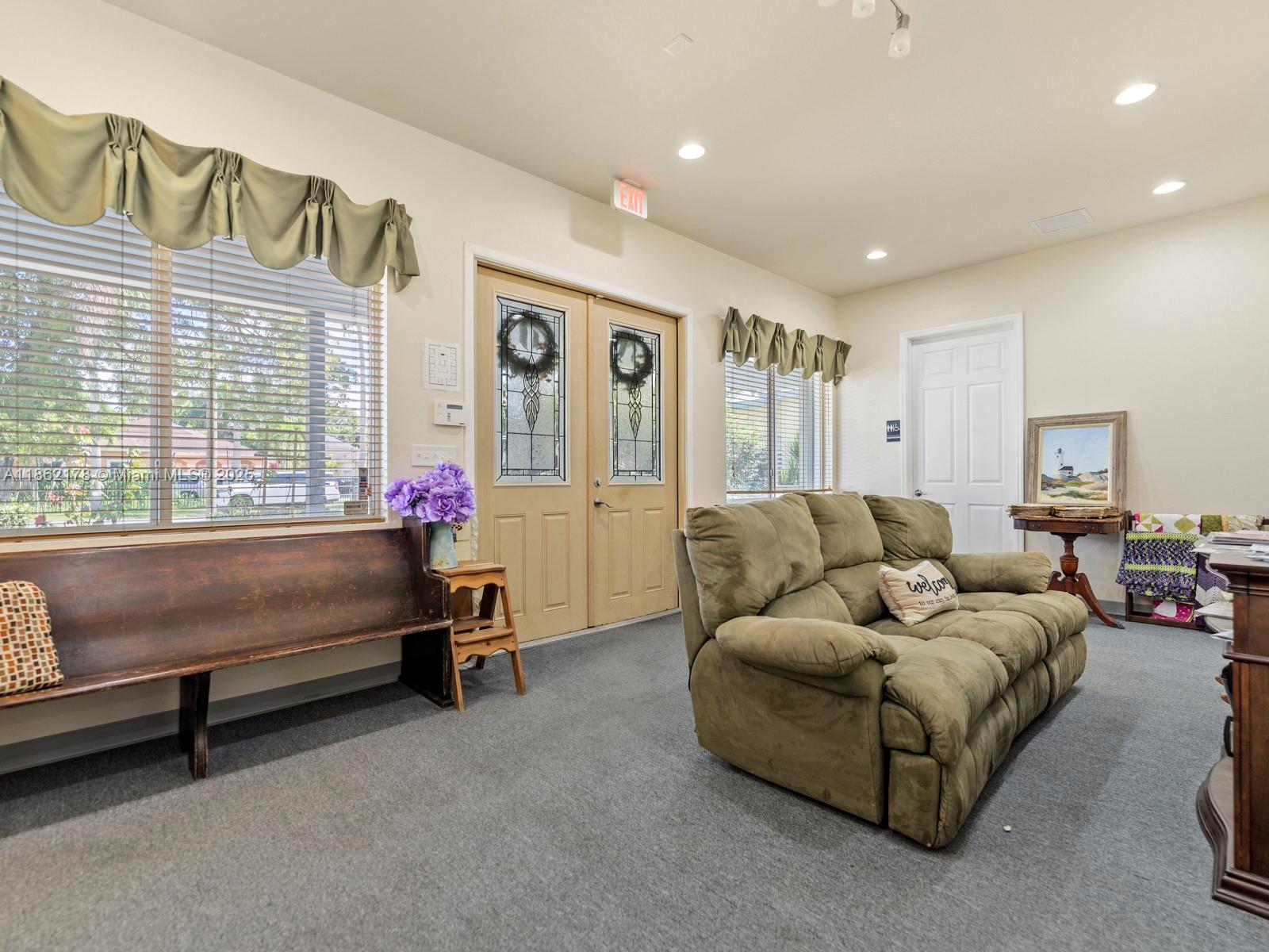 A waiting area features a wooden bench, a green sofa, double doors, and carpeted flooring — 45 NW 4th St, Homestead FL 33030, HOMESTEAD, FL