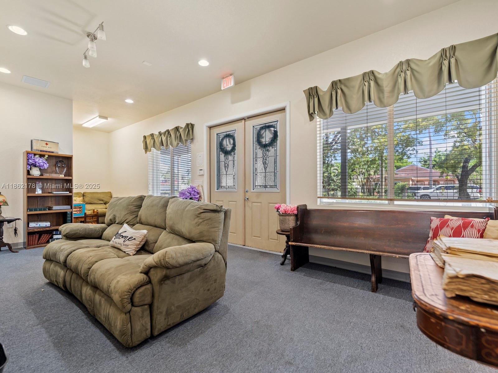 A living room features a green sofa, a wooden bench, double doors, and large windows — 45 NW 4th St, Homestead FL 33030, HOMESTEAD, FL